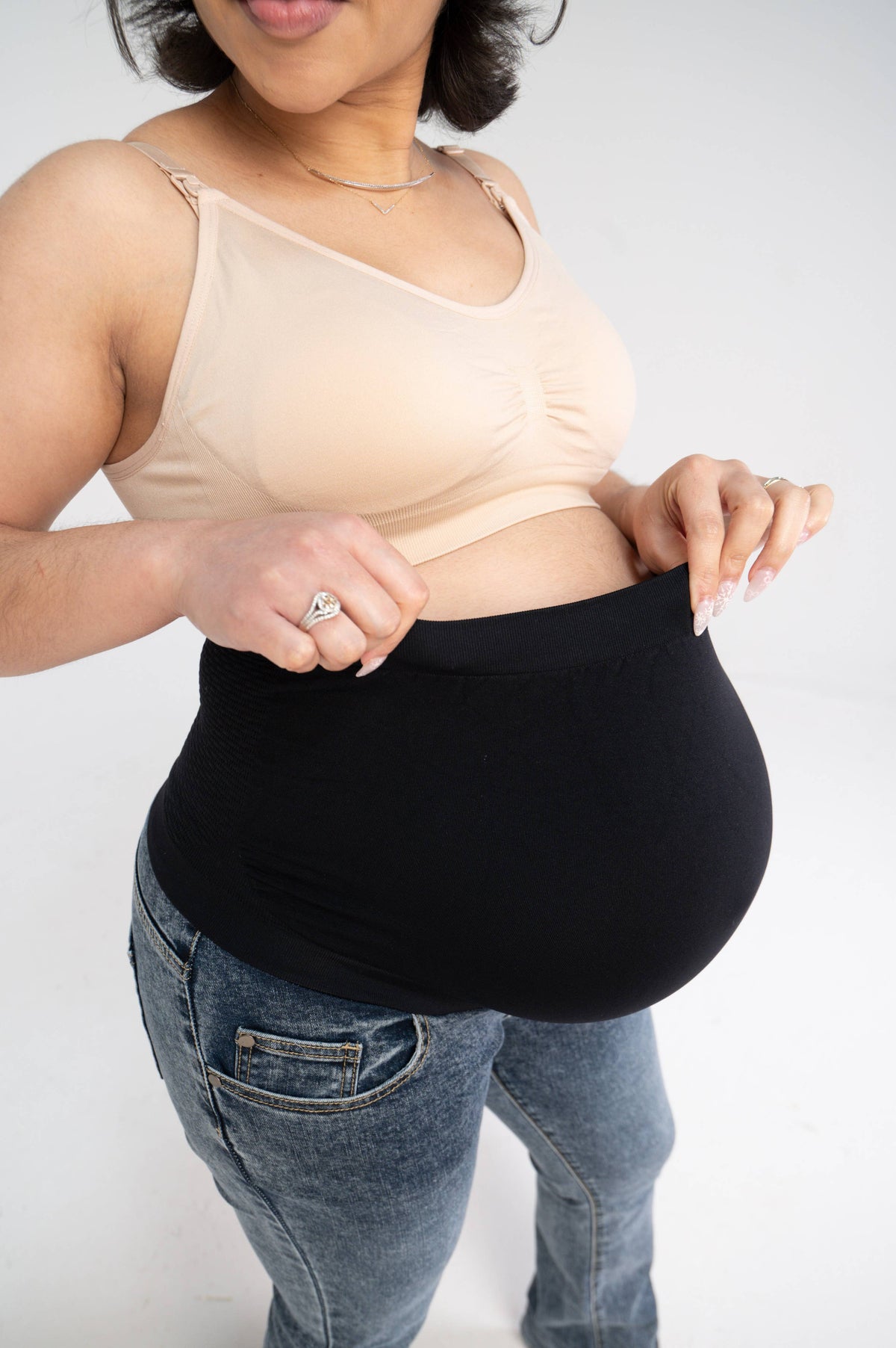 Woman adjusting the black over-the-belly waistband of the maternity jeans