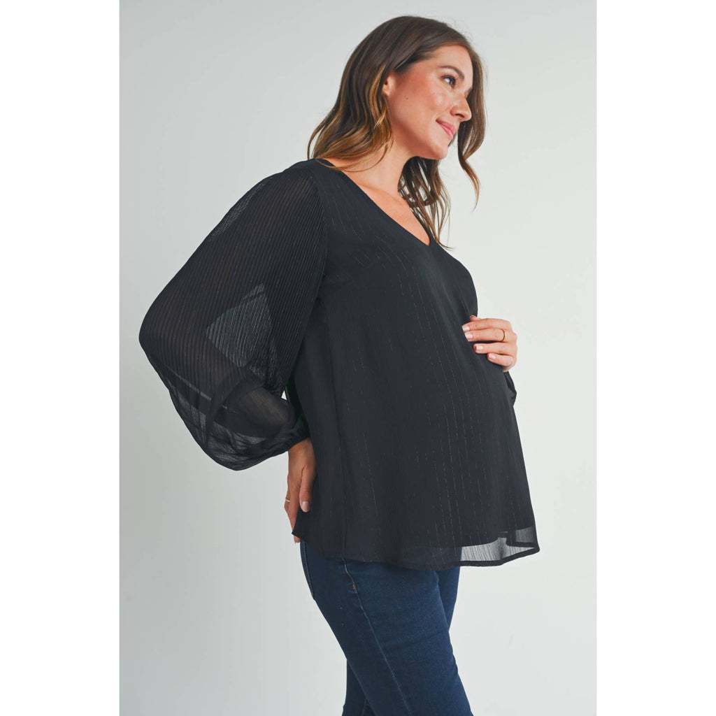 Woman in side profile with her hand on her pregnant belly, wearing the black maternity blouse
