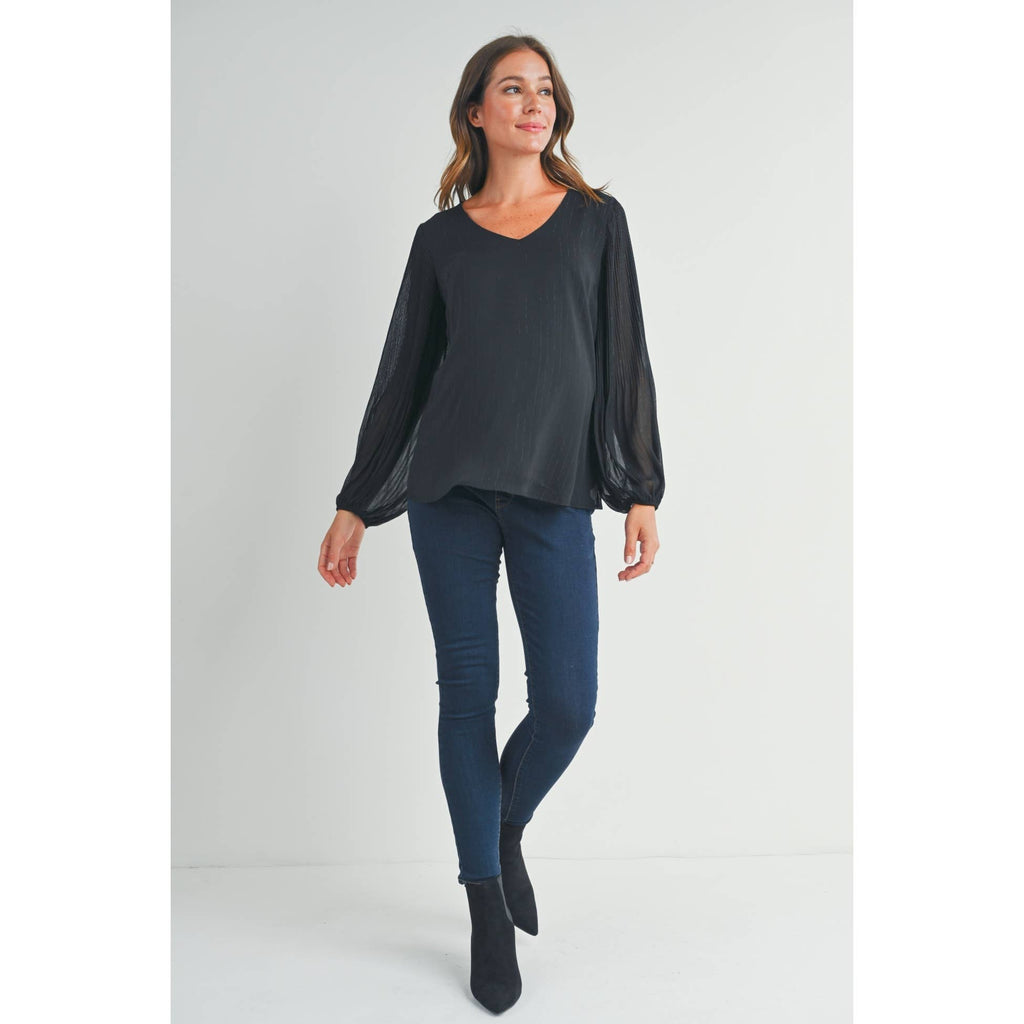 Full-body view of a woman wearing the black maternity blouse with dark jeans and black ankle boots