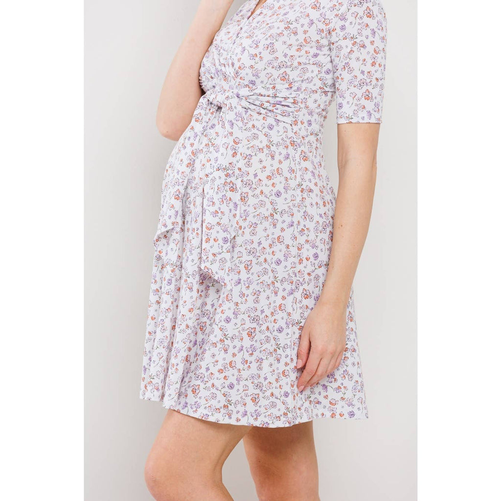 Woman is facing to the left wearing a floral maternity dress against a plain background, from the neck up she is out of frame 