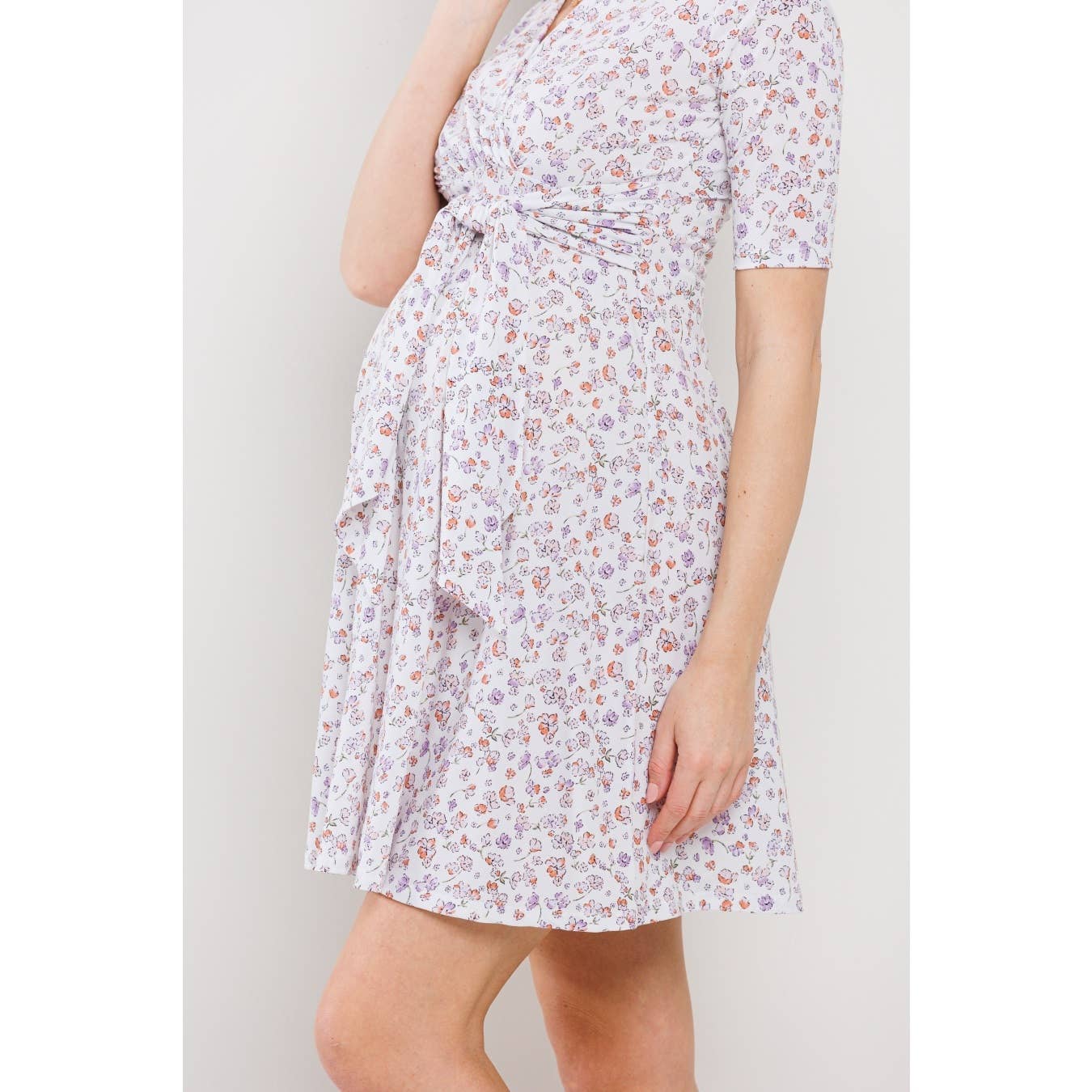 Woman is facing to the left wearing a floral maternity dress against a plain background, from the neck up she is out of frame 