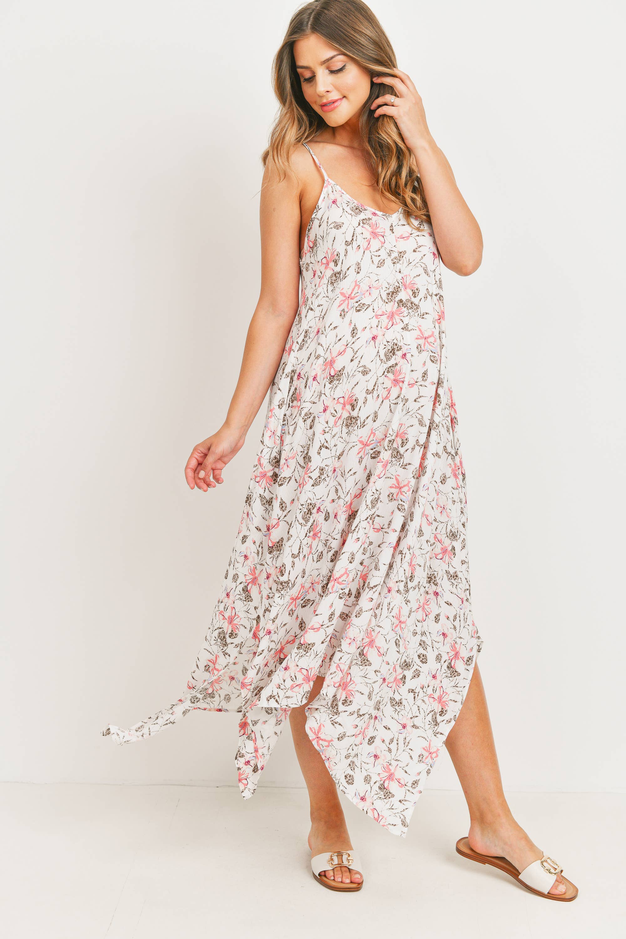 Woman facing to the right with her head turned back towards the left wearing a floral maternity dress on a plain background